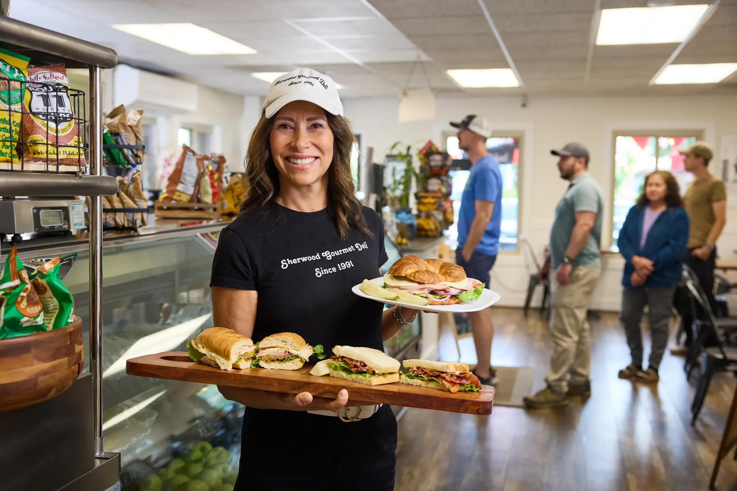 A Sherwood Gourmet Deli team member presents sandwiches.